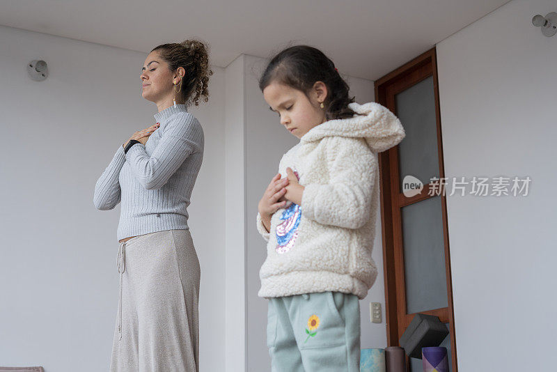 母亲和女儿在家里做瑜伽，享受一个非常私人的时刻，使他们更亲密