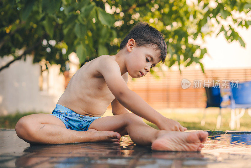 一个男孩在炎热的夏天过后用水降温。适合带孩子的家庭夏季户外活动。孩子们的聚会游戏。适合炎炎烈日的健康活动。