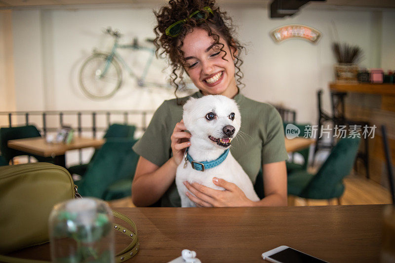 漂亮的少女在一家宠物友好的咖啡馆里喝咖啡