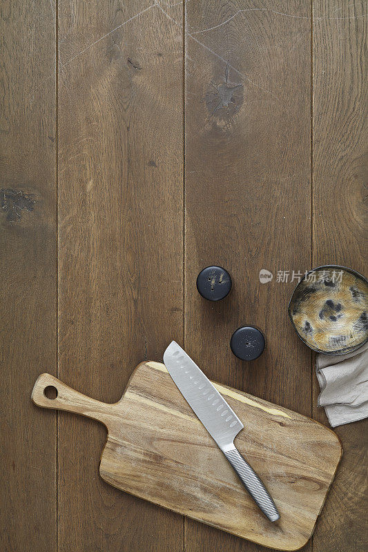 一把菜刀和一块空菜板放在一张质朴的棕色木桌上
