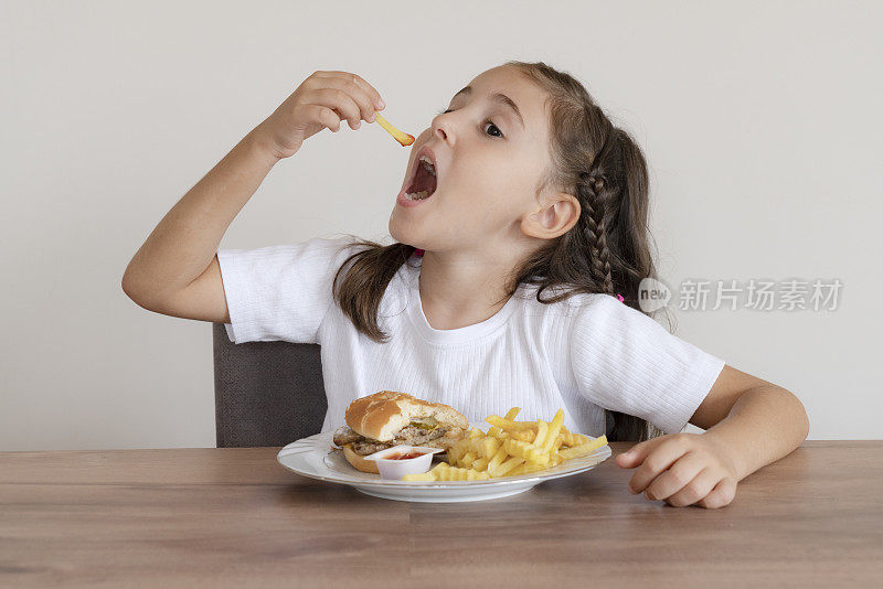 小女孩吃着一个大汉堡