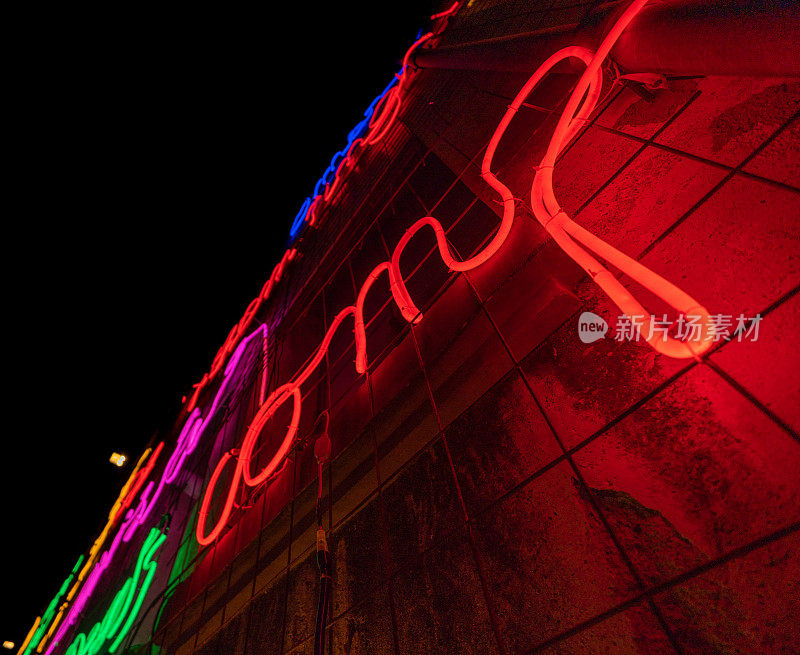 由霓虹灯和多种颜色的led灯以及红色和完全黑色的背景制成的发光字母和单词。爵士乐海报美学。电线和管子连接起来形成形状。