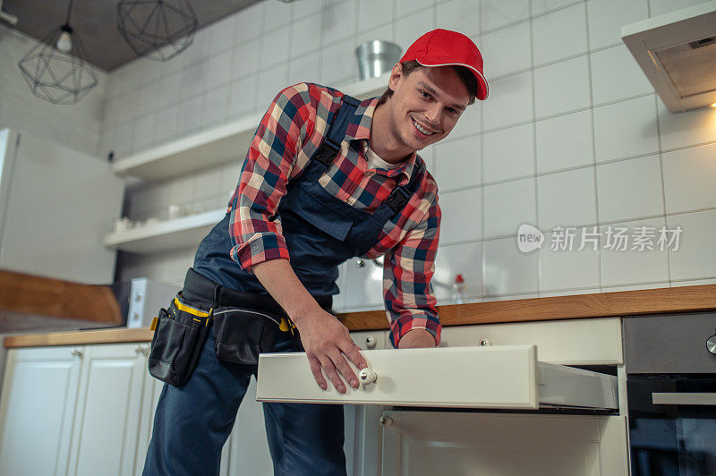 兴高采烈的修理工在客户的厨房里修理家具