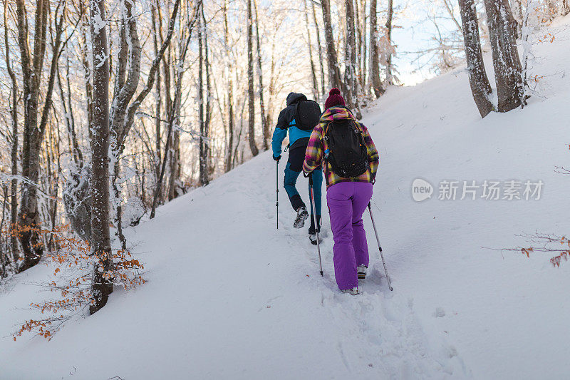 两个年轻的徒步旅行者在冬天爬上雪山