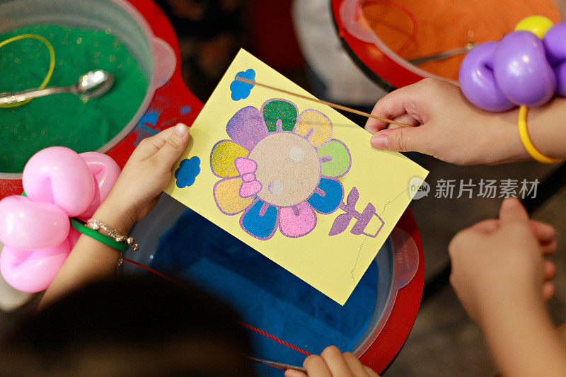 近距离的孩子享受手工工作，沙艺术画在贴纸卡。