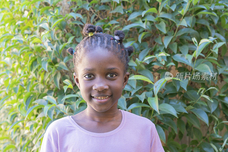 快乐的美国黑人小女孩的肖像在户外花园的背景微笑