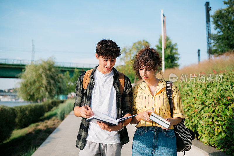 大学生们放学后在外面散步时一起复习他们的书