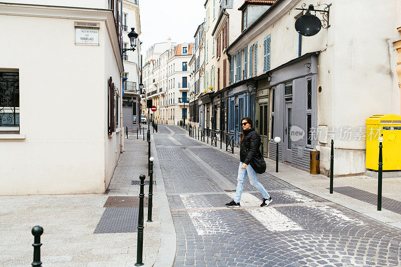 法国小镇上，一名妇女正穿过空荡荡的街道