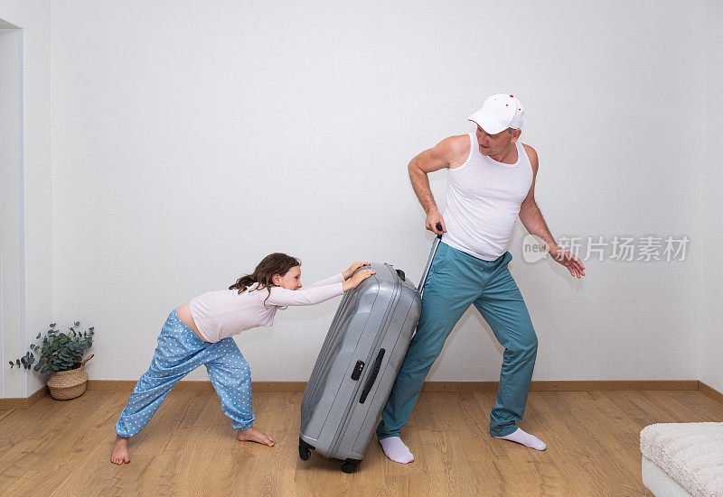 一名身穿白色t恤的白人男子和一名7岁的女孩提着一个又大又重的手提箱。一家人去旅行。