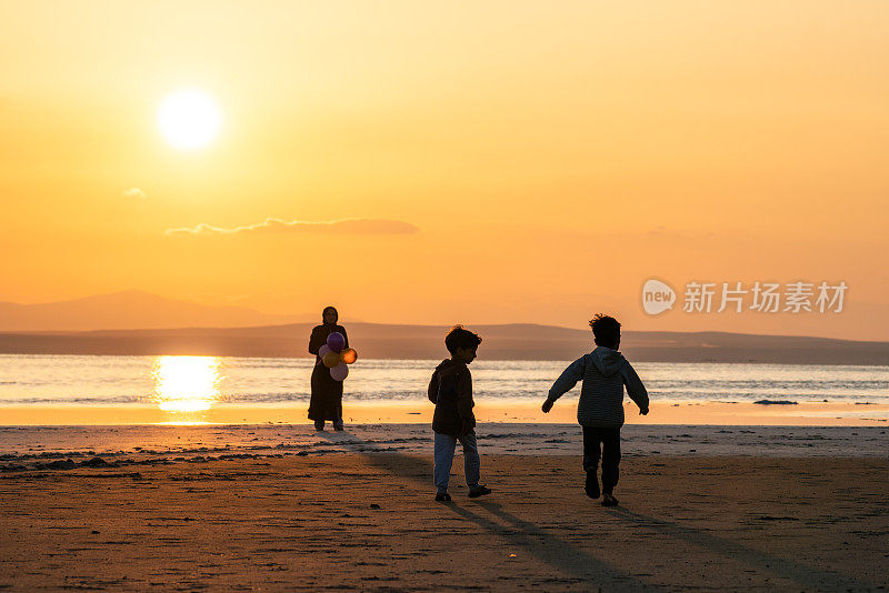 日落时分，母亲与孩子们在海滩上共度时光