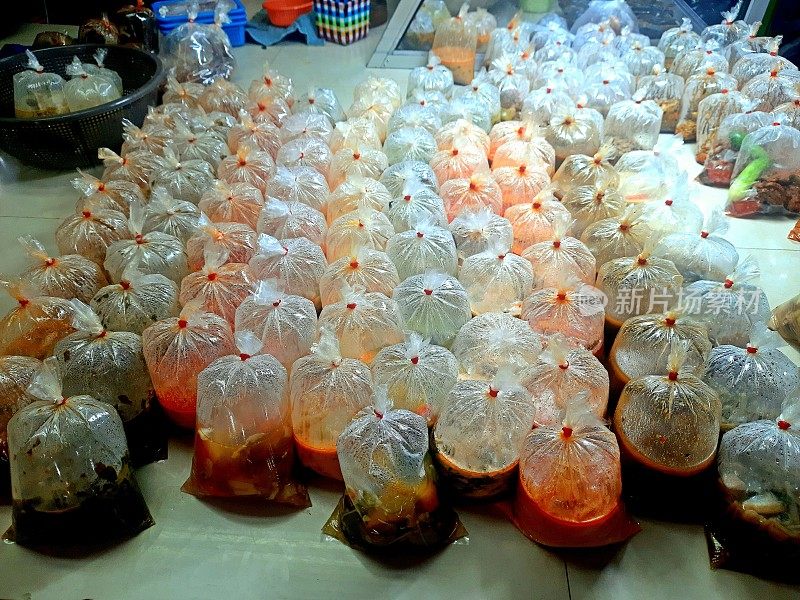 用橡皮筋捆扎的塑料袋取出食物——曼谷街头小吃。