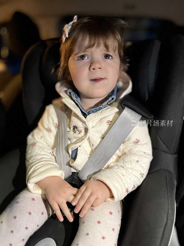 天黑后，蹒跚学步的孩子坐在汽车座椅上