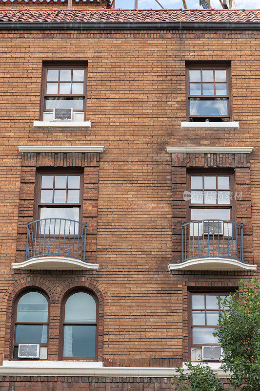 一栋老式砖砌公寓楼的正面，窗户和空调都清晰可见。