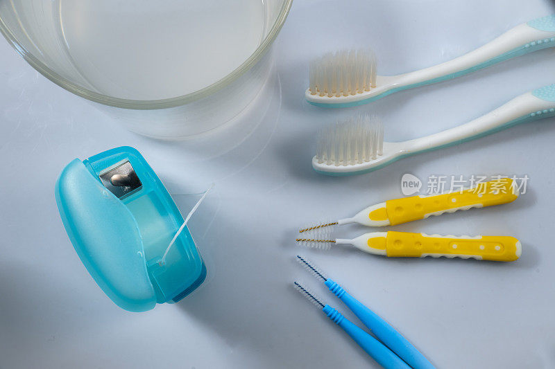牙齿护理用具:牙刷、牙线、牙间刷和一杯白底含药漱口水