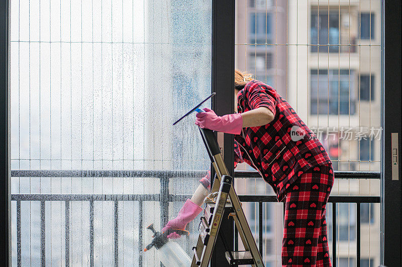 家庭主妇在家里擦窗户。中国家庭以大扫除来迎接春节