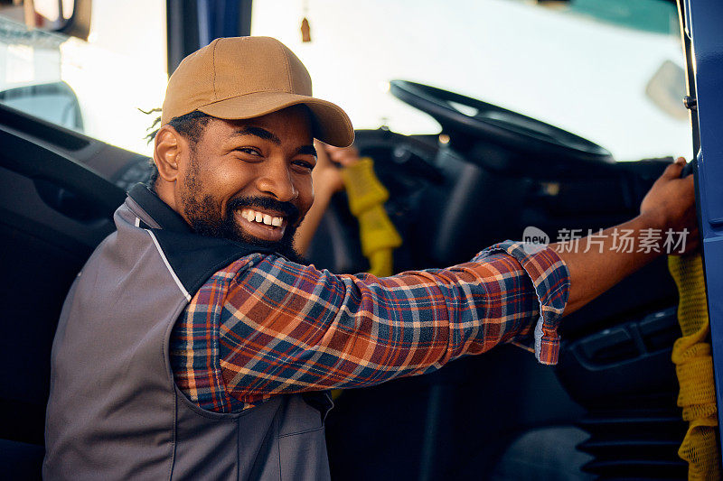 快乐的黑人职业司机钻进他的卡车，看着镜头。