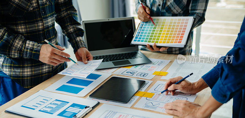 UX开发人员和ui设计人员在现代办公室里集思广益，根据客户简介和颜色代码设计移动应用程序界面线框。