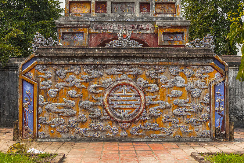 在越南顺化的一座皇城，华丽的石墙浮雕上有云的细节。拍摄于一个阳光明媚的日子。翻译过来就是:奠苴门
