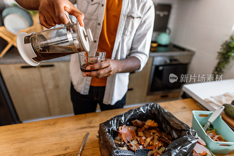 一名男子将用过的咖啡渣从咖啡壶倒入堆肥箱