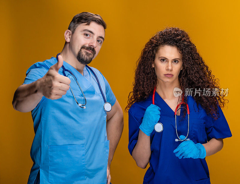 两名专业医生拿着听诊器看着摄像机，竖起大拇指，黄色背景
