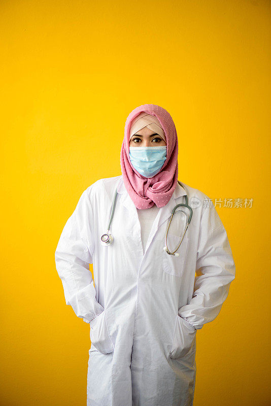 女穆斯林医生的肖像戴着头巾和外科口罩与黄色背景