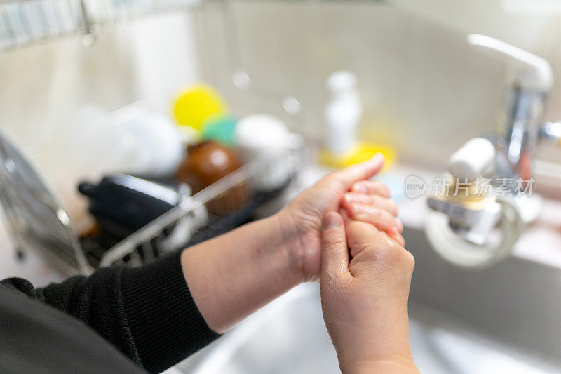亚洲妇女在厨房洗手后擦手霜