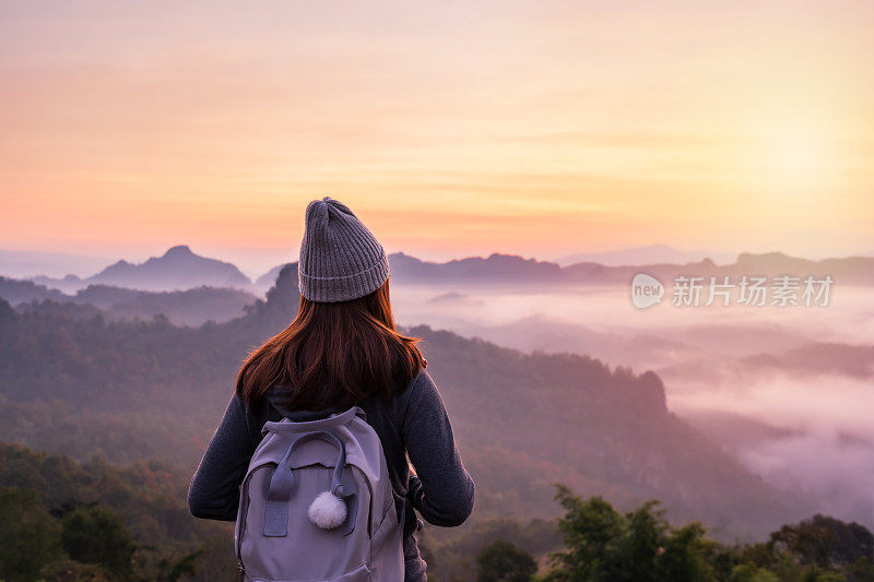 年轻的女旅人望着山上的云海和日落