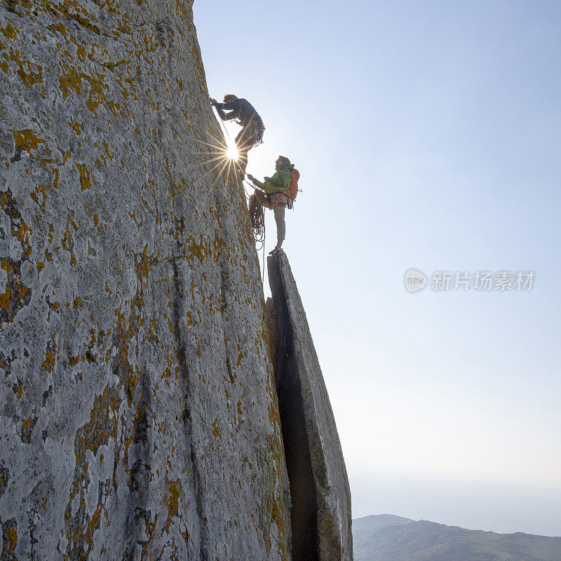 登山者在日出时攀登岩面