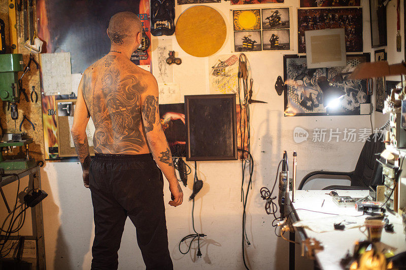 纹身艺术家与纹身头站在他的工作室，看他的艺术作品