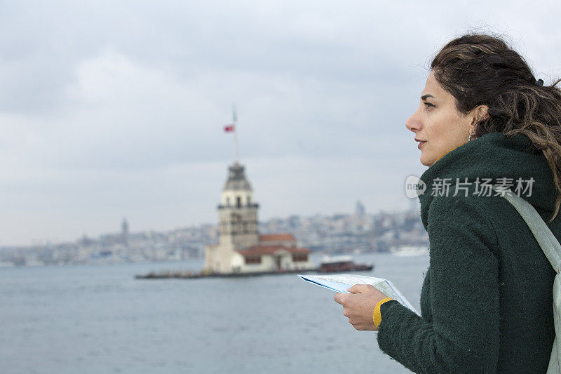 女孩正在研究乌斯库达海滨的地图，从那里可以看到少女塔