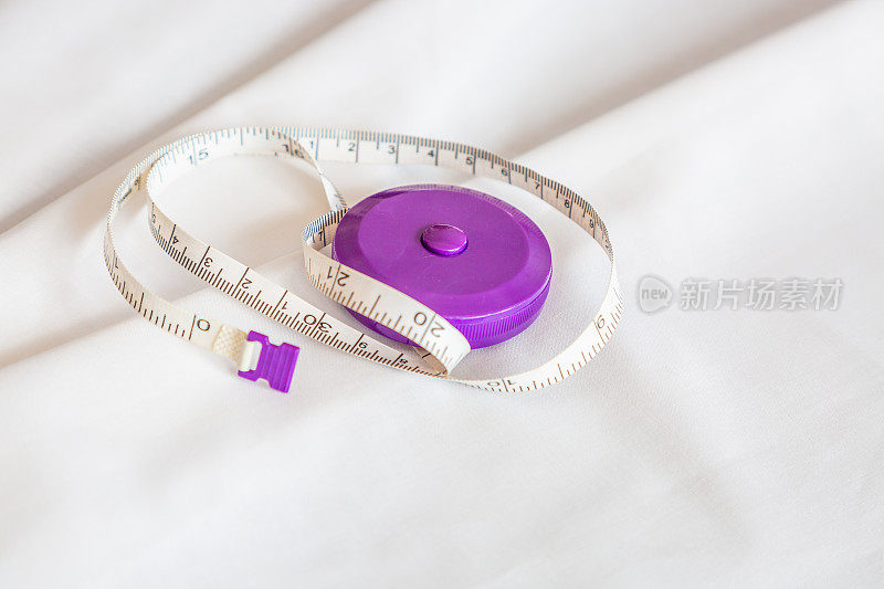 紫色卷尺在白色织物上测量