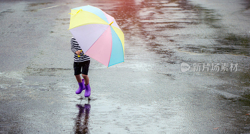 在一个下雨天，小人类拿着一把五颜六色的伞在雨中快乐地玩耍。