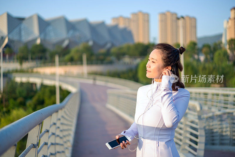 年轻的亚洲女性在锻炼后使用智能手机