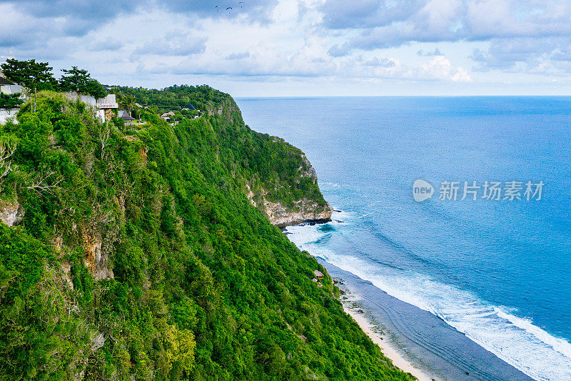 蓝色的海洋和被热带植物覆盖的悬崖。从上面看巴厘岛海岸。空中无人机拍摄。