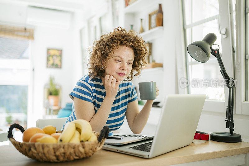 一个年轻漂亮的女人在家工作的侧视图