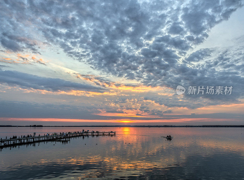 人们的剪影在码头湖边的黄昏与雄伟的云彩景观