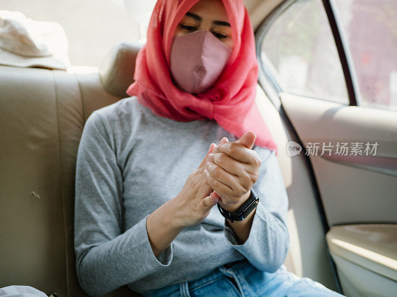 穆斯林妇女坐在车里使用洗手液