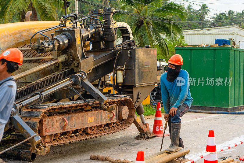 工人们拆除了道路上的一层沥青以铺设管道。在泰国岛上的街道上进行的维修施工工作