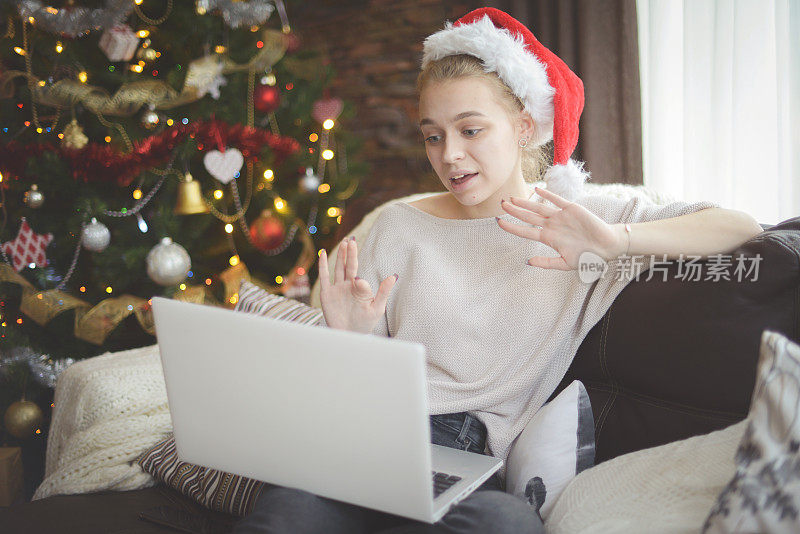 年轻女子在圣诞节室内与笔记本电脑(网上约会)