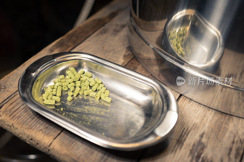 啤酒花颗粒躺在不锈钢托盘上的木地板准备放入麦芽汁，而酿造啤酒在车库在家里