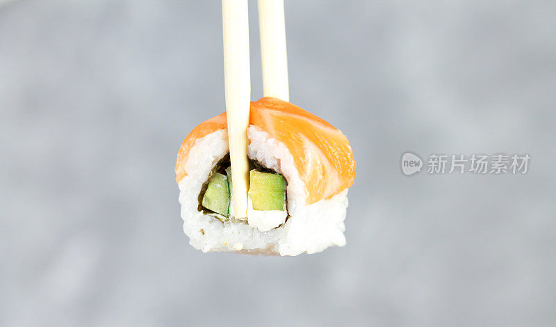 吃寿司费城卷与筷子特写，日本食物寿司卷在餐厅。