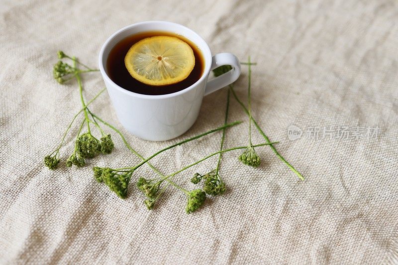 粗麻布白瓷大杯柠檬红茶，杯边有绿色的小野花