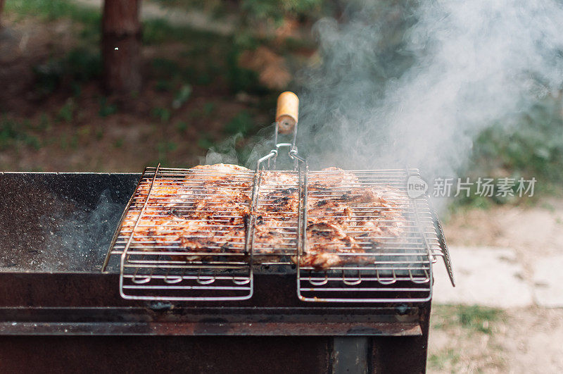 在烤架上用酱汁和香料煎腌过的鸡大腿。多汁的肉块浸在从木炭中冒出的烟中。在篝火上烤着炸鸡串。篝火做饭的季节。