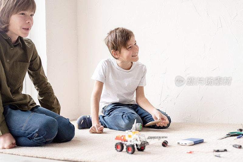 小男孩和老师在车间里快乐地建造机器人车，俯视图