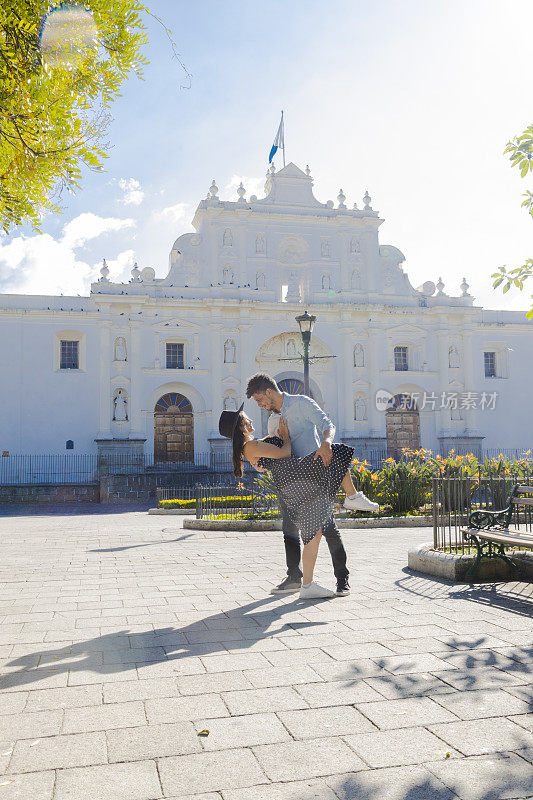 危地马拉安提瓜圣何塞大教堂前一对西班牙情侣相爱——阳光明媚的日子里，年轻的游客们在这座殖民城市里享受假期——情侣们在公园里玩耍。