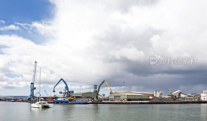 在英国多塞特的普尔港，一艘私人帆船漂过普尔码头入口的商业码头