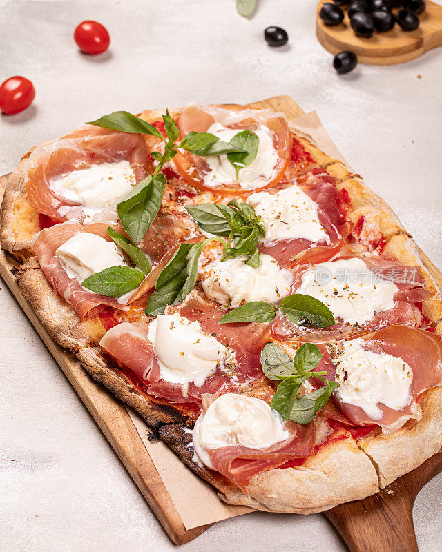 意大利罗马矩形披萨，意大利熏火腿和马苏里拉奶酪在木板上，白色乡村背景