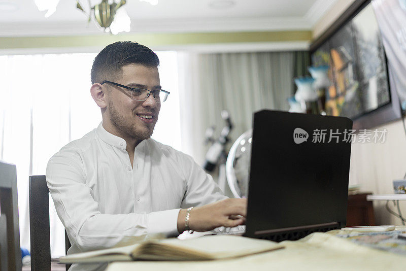 一名拉丁裔男子在家里用笔记本电脑工作