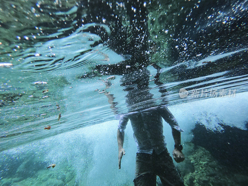一个不知名的成年男子穿着休闲装站在水里