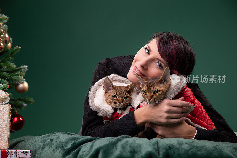 一个穿着暖和衣服的女人抱着她的两只猫